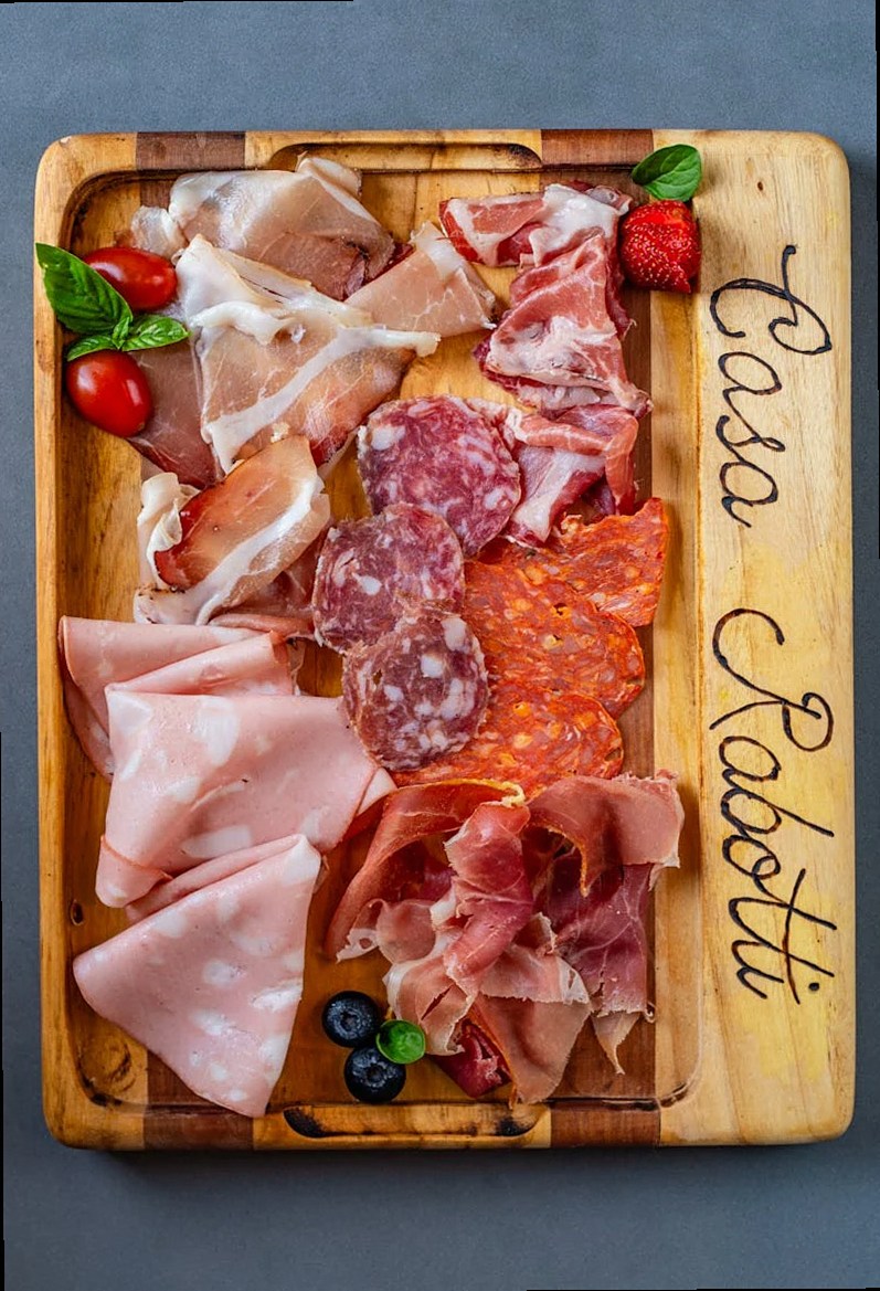 Viandes assorties sur une planche en bois avec garniture, créant un coloré étalage culinaire.